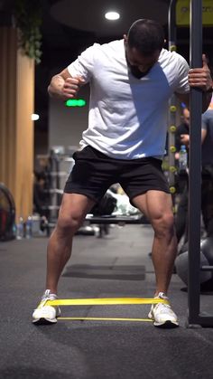 a man standing on top of a bar in a gym holding his hands behind his back