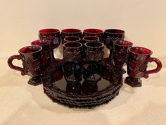 a table topped with lots of red glass cups and saucers