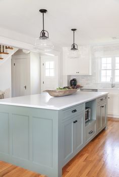 a large kitchen with an island in the middle and two pendant lights hanging from the ceiling