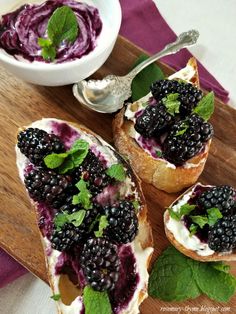 two pieces of bread with berries and cream on them next to a bowl of yogurt