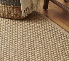 an area rug on the floor in front of a table with a basket and blanket