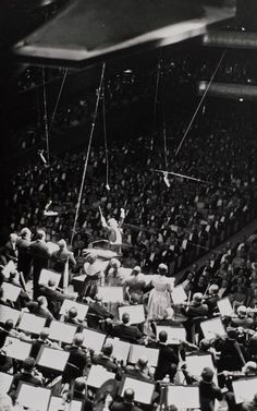 an old photo of a conductor and orchestra in the middle of a concert hall full of people