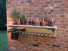 there are many potted plants on the shelf above the brick wall in this yard