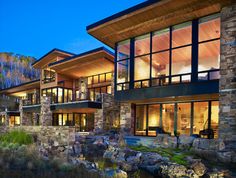 a large house with lots of windows next to a pond and trees in the background