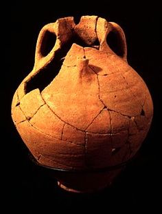 an old clay vase with holes in the bottom and sides, on a black background