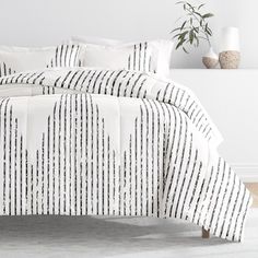 a white bed with black and white striped comforter set on it's side