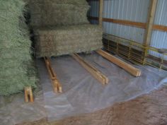 hay being stored in a barn with plastic covering the floor and pallets on the ground