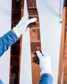 a person in white gloves is working on a piece of brown wood with the help of a ruler