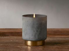 a grey candle sitting on top of a wooden table