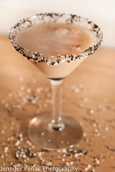 a close up of a drink on a table with confetti sprinkles