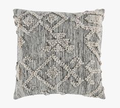 a gray and white pillow with an intricate design on the front, made out of knitted fabric