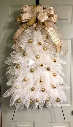 a christmas tree made out of tulle and gold bells on the front door with a bow