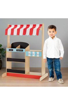 a young boy standing in front of a checkout booth with red and white striped awnings