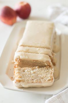 a white plate topped with slices of cake next to two pieces of fruit on a table