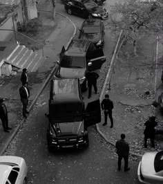 black and white photo of police officers standing around cars on the side of a road