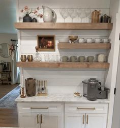 a kitchen with white cabinets and shelves filled with cups, saucers and other items