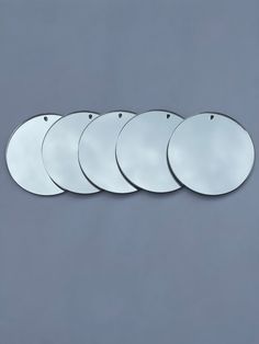 five mirrors are arranged in a row against a gray background, each with a different shape and size