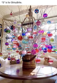 a table with a vase filled with lots of glass balls on it's branches