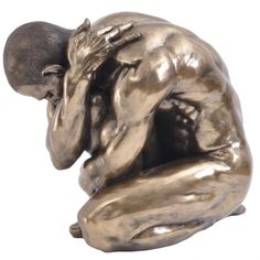 a bronze statue of a man with his head in his hands sitting on the ground