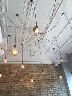 a brick wall with many lights hanging from it's ceiling and some wires running down the middle