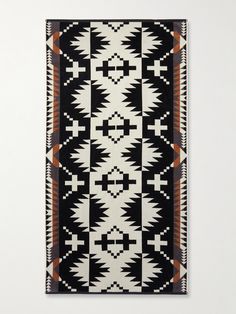 a black and white rug with an orange design on the bottom, in front of a white wall