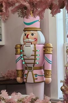 a nutcracker is standing next to a pink christmas tree