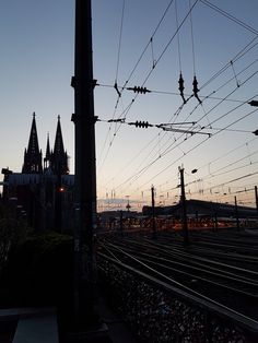 the silhouette of power lines and wires in front of a church at dusk with lights on