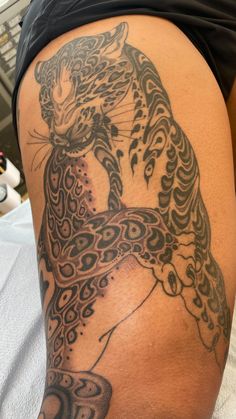 a woman's thigh with a tattoo on the side of her leg and a cat sitting on top of it