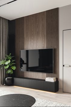 a living room with a large flat screen tv on the wall and a potted plant next to it