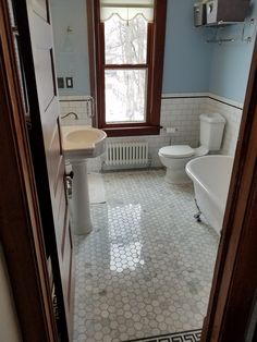 a bathroom with a toilet, sink and bathtub in the corner next to a window