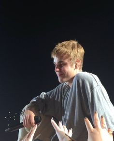 a young man sitting on top of a stage with his hands in the air