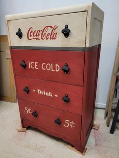 an old coca - cola ice cold chest is painted red and white with black knobs