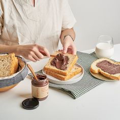 a person is spreading chocolate frosting on some bread and peanut butter in a bowl