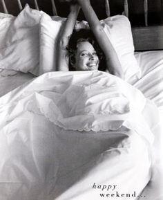 a woman laying in bed with her arms up above her head and smiling at the camera