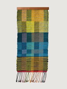 a multicolored woven wall hanging with tassels