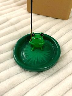 a frog sitting on top of a green frisbee in the middle of a bed