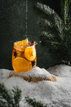 a glass filled with liquid sitting on top of snow