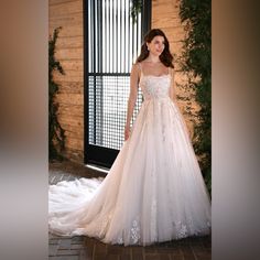 a woman in a white wedding dress standing next to a window with ivy growing on it