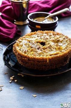 a cake on a black plate next to a bowl of oatmeal and spoon