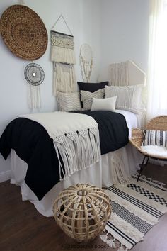 a bedroom with black and white bedding, wicker chair, rattan headboard and macrame wall hangings