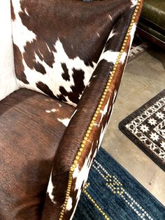 a brown and white cow print chair sitting on top of a blue rug