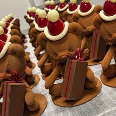 some very cute little brown teddy bears with presents in their hands and santa hats on