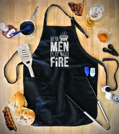 an apron that says real men play with fire surrounded by other cooking utensils