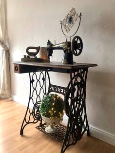 an old fashioned sewing machine is sitting on a table with a potted plant in front of it