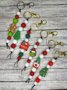 several christmas themed key chains on a wooden table with other items in the shape of santa's helpers