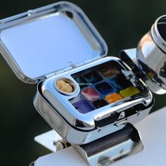 a silver box with some food inside of it on a table next to a cup and saucer