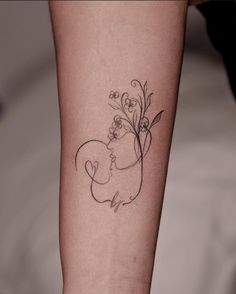 a woman's arm with a tattoo on it that has flowers and a bear