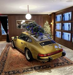 a yellow car with a christmas tree on top in a room filled with large windows