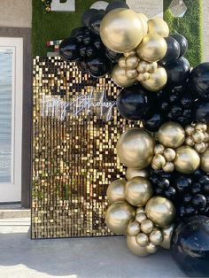 a bunch of black and gold balloons hanging from the side of a building