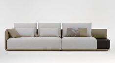 a couch with several pillows on it sitting in front of a white wall and floor